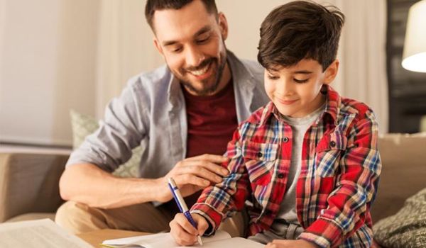 A father is shown helping his son with homework.