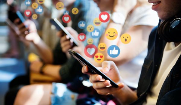 Social media engagement icons floating out from a phone held in a hand