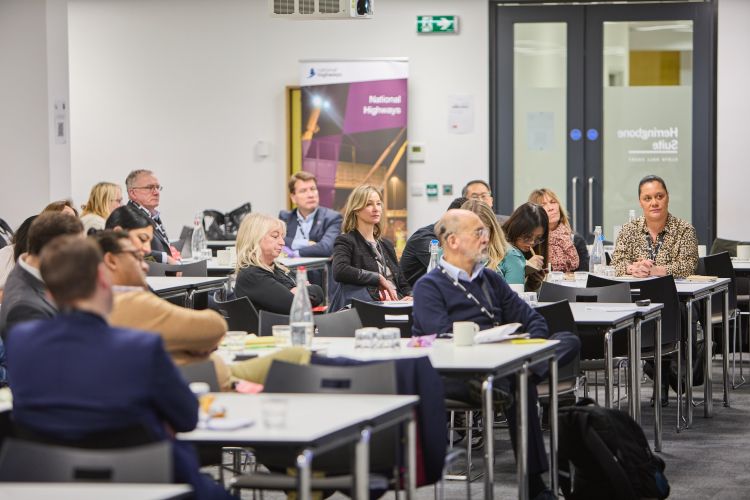 The image shows an engaged Ideas in Practice audience watching event presentations.