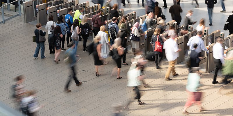 Commuters at a busy train station walking through ticket barrier