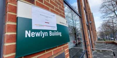 Newlyn building sign with assessment centre and a directional arrow