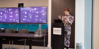 Person stood by podium presenting to a room.