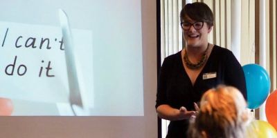 picture of Stacey Mottershaw presenting and slide with sign 'I cannot do it' being cut with scissors