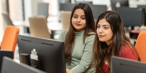 Two students looking at a computer screen in the Esther Simpson Building IT cluster.