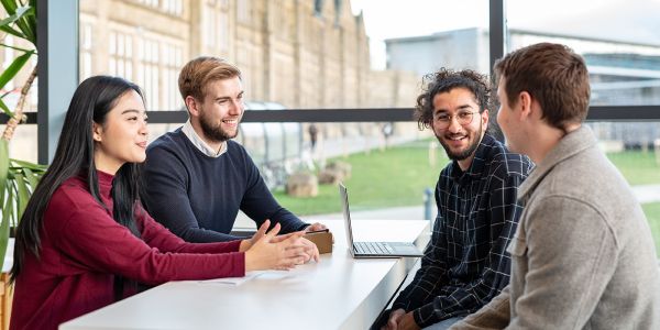 A group of Masters students working together using a laptop