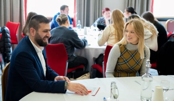 Two members of the Leaders in Residence network talking to each other, sat at a table