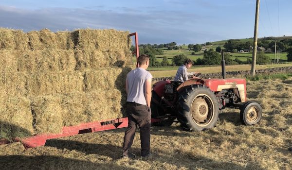 Farmer on tractor loaded with hay