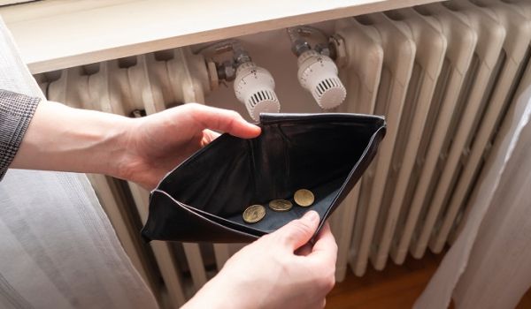 Open wallet with only a few coins in, next to a radiator