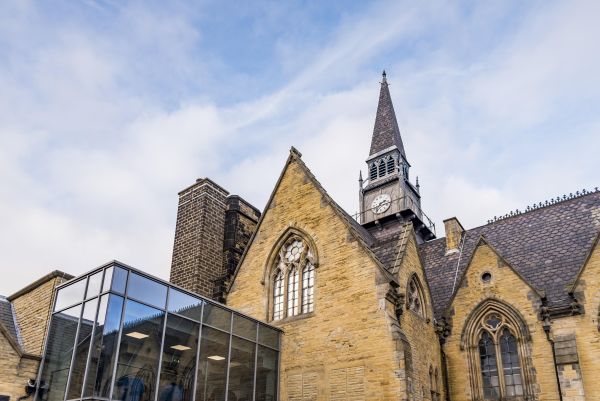 Brick building with modern glass extension against blue sky