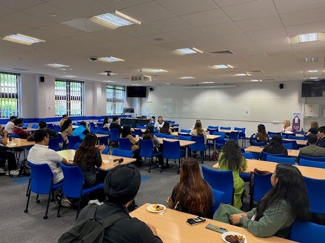 Students in a classroom attentively listening to an alumni speaker.