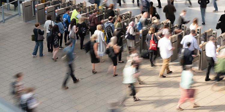 Commuters at a busy train station walking through ticket barrier