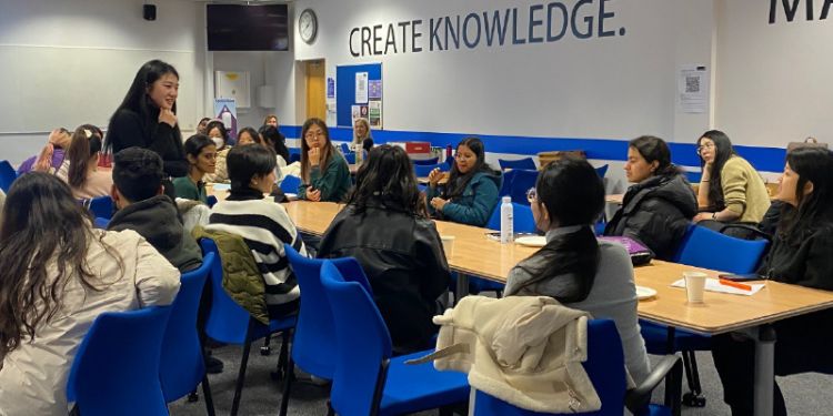 A women standing up speaking to students that are sitting down in a seminar room