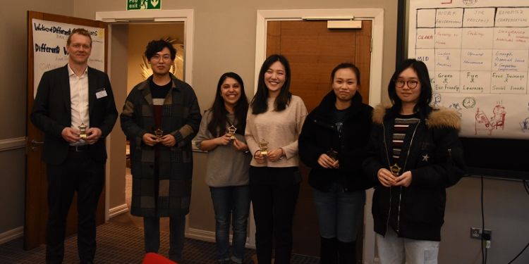 The winning team stands holding their trophies.