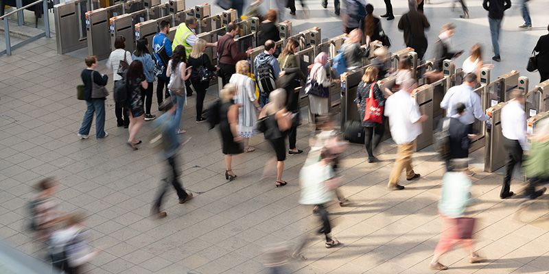 Commuters at a busy train station walking through ticket barrier